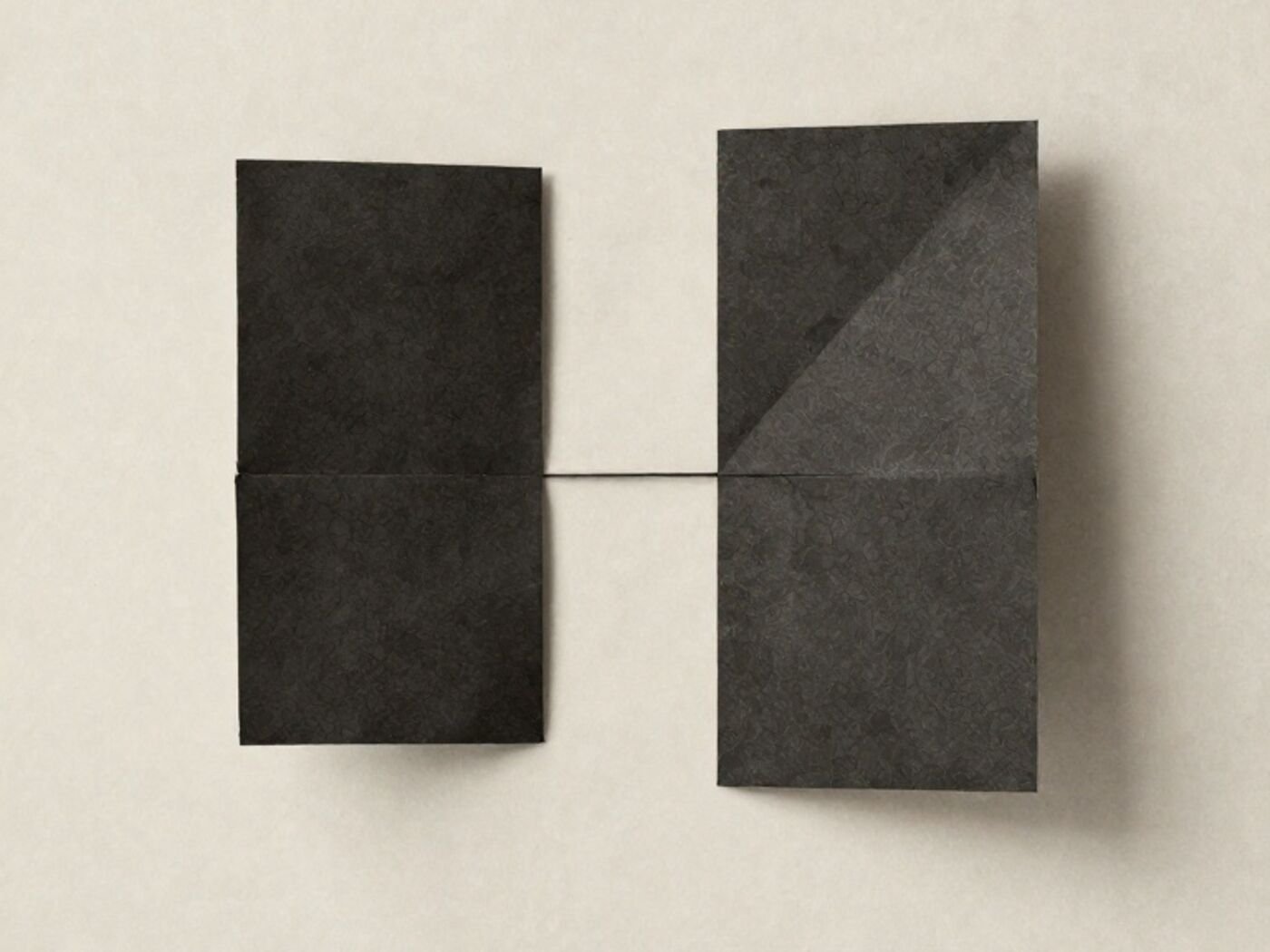 Two folded paper forms of different geometry either side of a single hairline seam