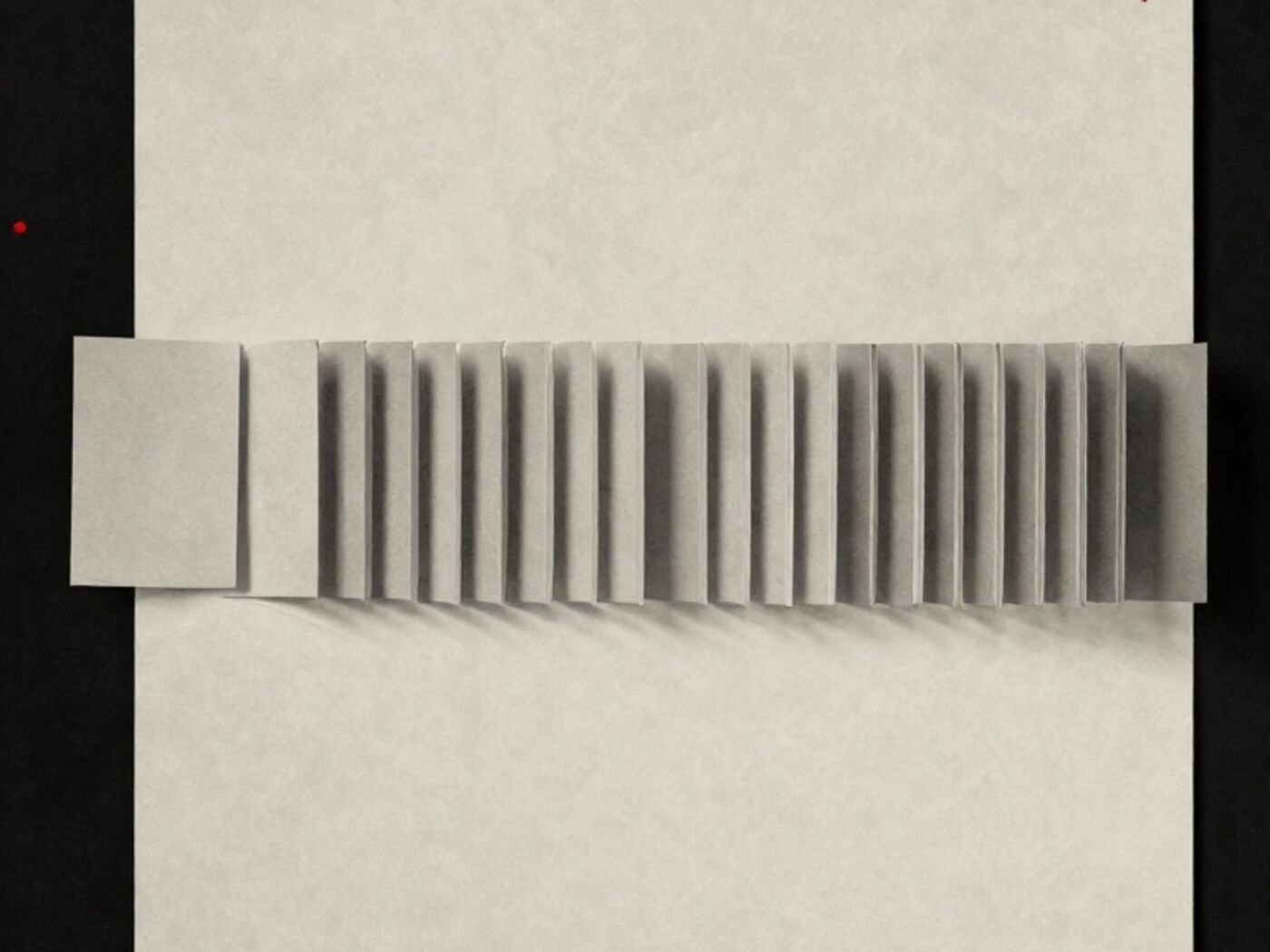 A row of identical paper cards lying flat, with one lifted and standing on its edge
